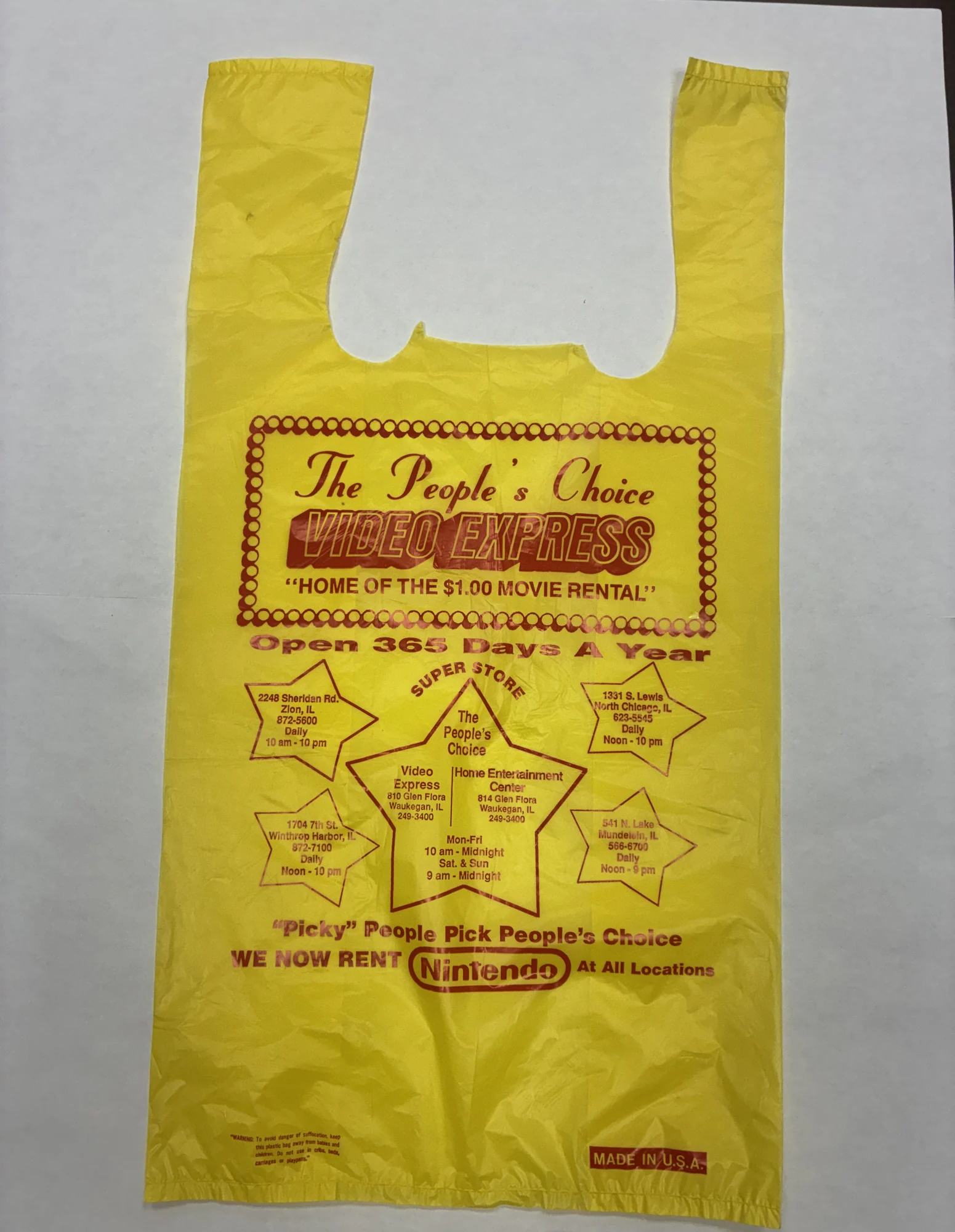 A 1989 yellow People’s Choice Video Express plastic movie bag printed with the $1.00 movie rental slogan and a star map of store locations.