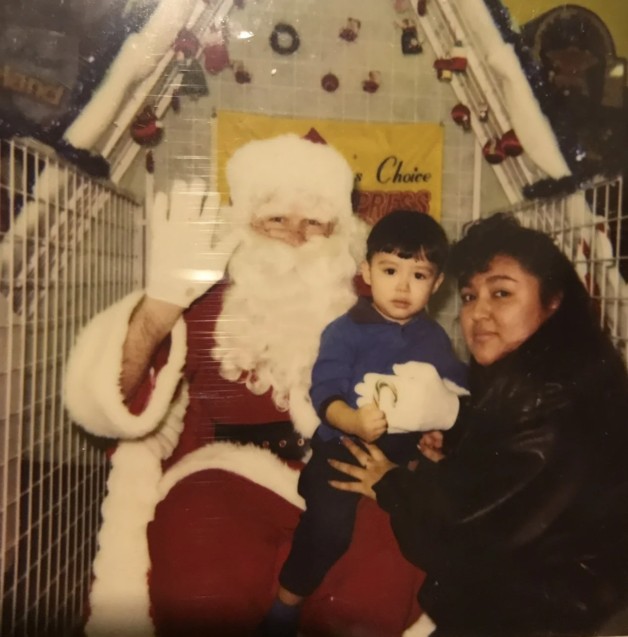 A mother holds her young son on Santa’s knee inside a decorated photo house at People’s Choice Video Express, December 9, 1996.