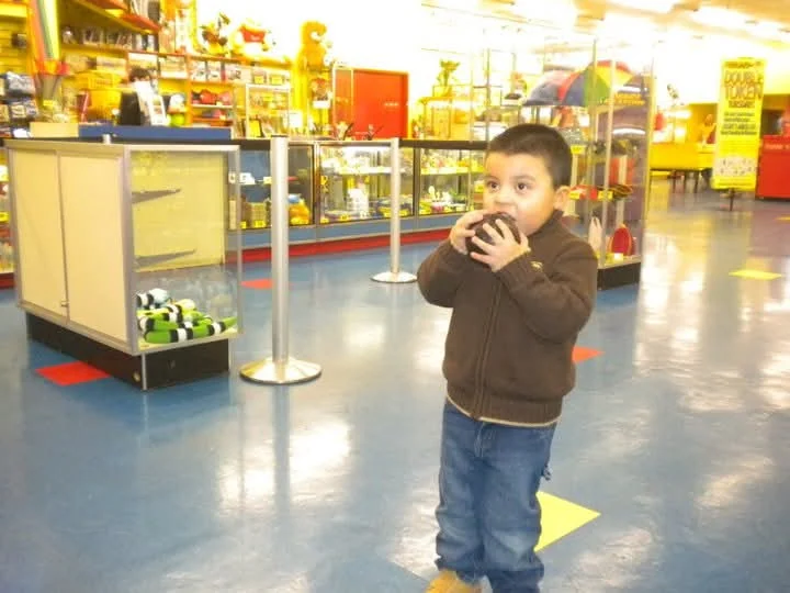A small boy in a brown jacket stands in front of the prize counter and display cases at People’s Choice Family Fun Center in 2011.