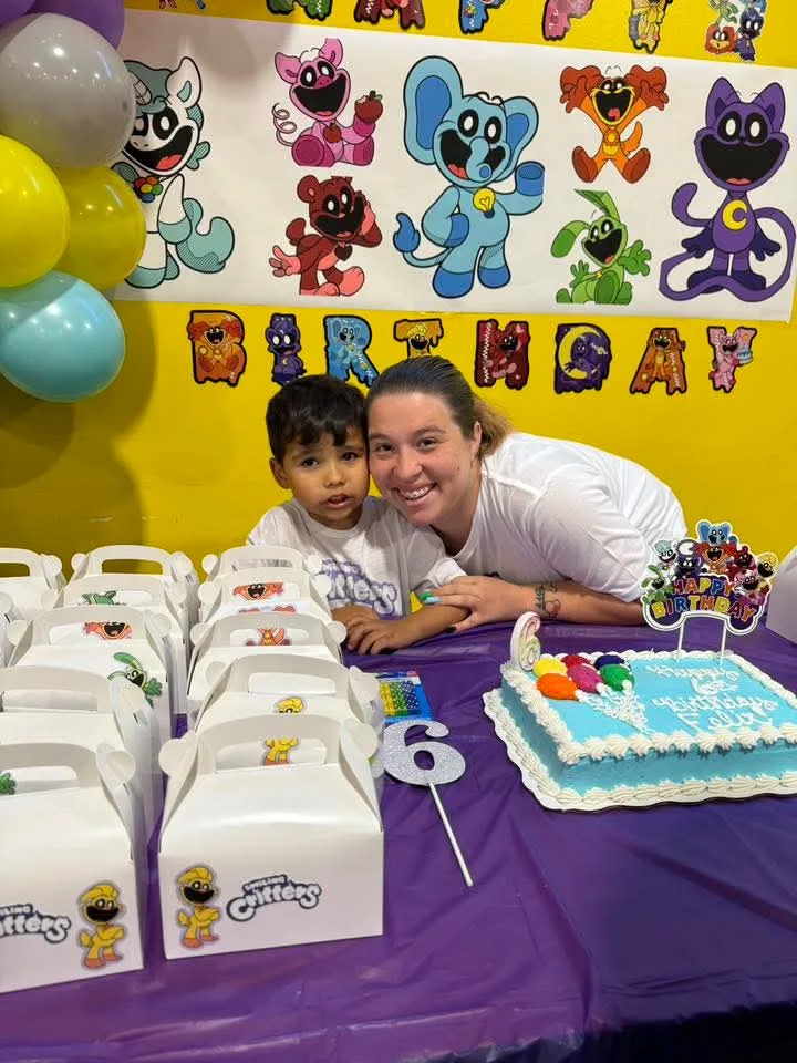 A mother and her son pose with his sixth birthday cake and party favor boxes in the People’s Choice party room, 2024.