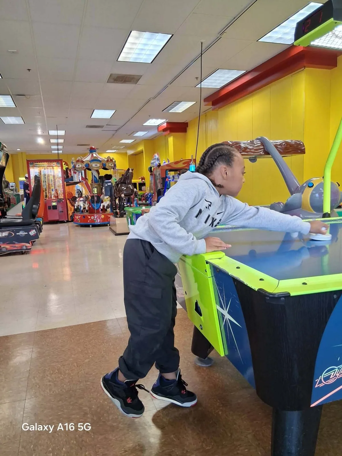 A child leans over the air hockey table at People’s Choice Family Fun Center — Jacqueline Diehn, August 1, 2026: “Spent time with my friend and the kids.”